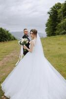 A beautiful young bride, in a summer park, walks ahead of her groom. Beautiful wedding white dress. Walks in the park. A happy and loving couple. photo