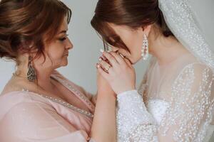 A beautiful and happy mother and her daughter, the bride, are standing next to each other. The best day for parents. Tender moments at the wedding. photo