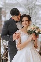 Happy couple kissing in winter. Couple embracing in snowy winter park.Winter wedding of stylish beautiful young couple bride and groom photo