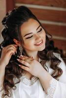 A beautiful brunette bride with a tiara in her hair is getting ready for the wedding in a beautiful robe in boudoir style. Close-up wedding portrait, photo. photo