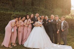 full-length portrait of the newlyweds and their friends at the wedding. The bride and groom with bridesmaids and friends of the groom are having fun and rejoicing at the wedding. photo