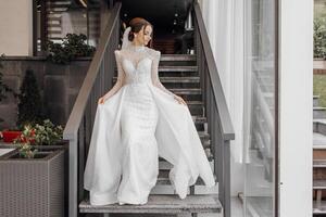 a full-length bride in a fashionable wedding dress on the steps of a restaurant walks forward and shows off her dress. Wedding day. The best event photo