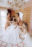 Friends rejoice with the bride in the morning. They take pictures, smile, help the bride fasten her dress. photo