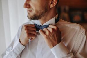 man's tie in hands, close-up photo of hands. The groom is preparing for the ceremony. Last preparations.