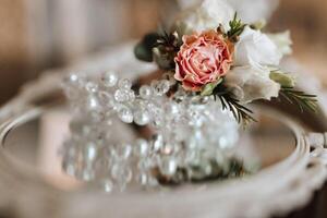 The groom's boutonniere and the bride's jewelry on the mirror. Wedding details photo