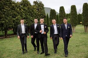 Cheerful, young, energetic witnesses of the groom next to the groom. Friends congratulate the groom. Groom and his funny friends having fun on the wedding day of the newlyweds. photo