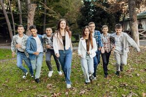 friendship, movement, action, freedom and people concept - group of happy teenagers or school friends posing and having fun outdoors against nature or forest background. photo