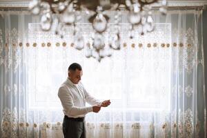 A man poses and fastens a black jacket. Portrait of the groom. Fashion and style. Business photo