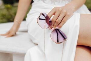 pink beautiful gold-rimmed sunglasses in female hands close-up photo