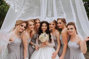 grupo retrato de el novia y damas de honor un novia en un Boda vestir y damas de honor en plata vestidos sostener elegante ramos de flores en su Boda día. foto