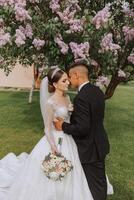 Wedding. Love and couple in garden for wedding. Celebrating the ceremony and commitment. Save the date. Trust. The bride and groom embrace against the background of a spring blooming tree. photo