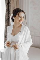 retrato de novia niña en blanco túnica con profesional peinado y natural maquillaje en hotel habitación con maravilloso interior foto