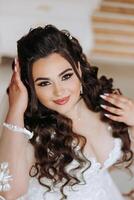 A wonderful beautiful portrait of a young bride. Beautiful bride with wedding makeup and jewelry wreath on long curly hair. Wedding photo model with brown eyes in a beautiful interior.