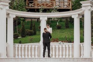 The bride and groom embrace near the Roman-style columns. An exquisite wedding photo