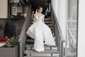 a full-length bride in a fashionable wedding dress on the steps of a restaurant walks forward and shows off her dress. Wedding day. The best event photo