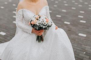 The bride is wearing a white voluminous dress with a long train, holding a bouquet and posing. Cropped photo. Winter wedding. photo