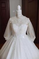 Bedroom interior with wedding dress prepared for the ceremony. A beautiful lush wedding dress on a mannequin in a hotel room. photo