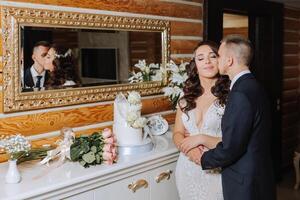 boda. novio y novia cerca el Boda pastel. un dulce y delicioso postre para un boda. el novia cortes el Boda pastel con el ayuda de su amante. el novio abraza su amado. foto