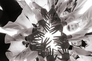 un grande grupo de sonriente joven personas de pie, abrazando, mirando a el cámara y extensión su brazos abajo. grupo de alegre Adolescente personas en un circulo mirando abajo. bajo visita ángulo. Copiar espacio. foto