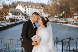 Winter wedding. Happy couple walking in wedding clothes hugging and smiling in a winter park covered with snow on their wedding day. Winter love story of a beautiful couple in snowy winter weather photo