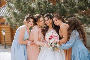 Group portrait of the bride and bridesmaids. A bride in a wedding dress and bridesmaids in beautiful dresses hold the bride's bouquet on the wedding day. photo