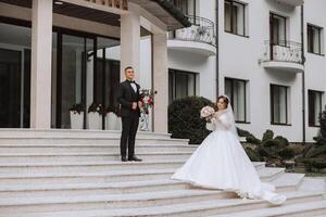 portrait of the newlyweds in classic wedding clothes on a large beautiful staircase. the concept of stores and sales of goods for the bride and groom. photo