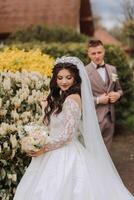 un hermosa joven novia, en un verano parque, camina adelante de su novio. hermosa Boda blanco vestido. camina en el parque. un contento y amoroso Pareja. foto