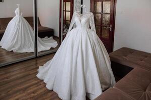 Bedroom interior with wedding dress prepared for the ceremony. A beautiful lush wedding dress on a mannequin in a hotel room. photo