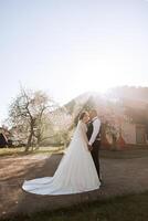 Wedding. Love and couple in garden for wedding. Celebration of ceremony and commitment. Save the date. Trust. The groom embraces the bride against the background of spring blossoming trees. photo