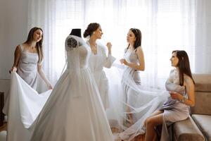 Friends rejoice with the bride in the morning. They take pictures, smile, help the bride fasten her dress. photo