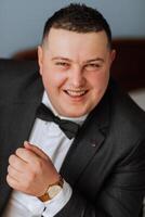 Stylish portrait of the groom. A man prepares for a wedding ceremony in the morning. Groom's morning. Preparation for the groom's morning. Young and handsome groom in a stylish suit. photo