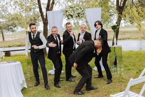 alegre, joven, energético testigos de el novio siguiente a el novio. amigos felicitar el novio. novio y su gracioso amigos teniendo divertido en el Boda día de el recién casados. foto