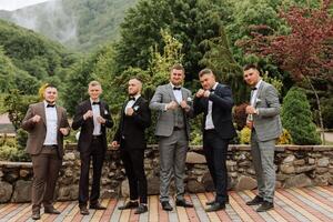 Cheerful, young, energetic witnesses of the groom next to the groom. Friends congratulate the groom. Groom and his funny friends having fun on the wedding day of the newlyweds. photo