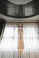 Bedroom interior with wedding dress prepared for the ceremony. A beautiful lush wedding dress on a mannequin in a hotel room. photo