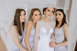 Friends rejoice with the bride in the morning. They take pictures, smile, help the bride fasten her dress. photo