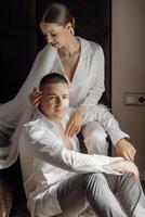 Sensual and tender morning of the bride and groom in the hotel room. Confident girl bride and handsome boy groom. Preparation for the wedding photo