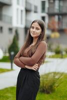 Vertical photo. Beautiful carefree young teenage girl in casual clothes. Portrait of a beautiful girl against the background of nature with a blurred background. photo