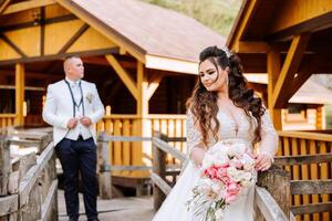 A beautiful young bride, in a summer park, walks ahead of her groom. Beautiful wedding white dress. Walks in the park. A happy and loving couple. photo