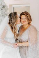 A beautiful and happy mother and her daughter, the bride, are standing next to each other. The best day for parents. Tender moments at the wedding. photo