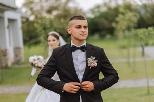 A beautiful young bride in a summer park is walking to her groom. Photo of the groom in the foreground. Selective focus. Beautiful wedding white dress. Walks in the park. A happy and loving couple.