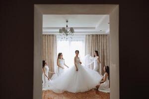 Friends rejoice with the bride in the morning. They take pictures, smile, help the bride fasten her dress. photo