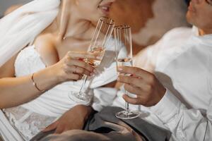 portrait of newlyweds in hotel lying on sofa with glasses of champagne, close-up. The groom gently touches the bride. After the wedding ceremony. Happy bride and groom celebrating photo