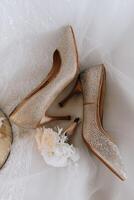 The bride's engagement ring, fashionable stilettos, fresh rose flowers. Wedding details in golden style. photo