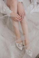 The bride puts on her wedding shoes. Elegant bridal shoes. Close-up photo. Preparation for the wedding ceremony photo