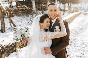 Boda retrato de el novia y novio. invierno caminar en naturaleza. el novia abraza el acicalar, mirando a cada otro. foto