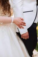 el novia sostiene el del novio mano. recortado foto. novio en un blanco traje. detalles foto