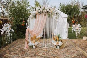 boda. Boda ceremonia. arca. un arco decorado con rosado y blanco flores soportes en el patio, en el zona de el Boda ceremonia foto