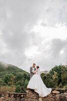 Wedding. Love and couple in garden for wedding. Celebration of ceremony and commitment. Save the date. Trust. The groom embraces the bride against the background of mountains and a cloudy sky. photo