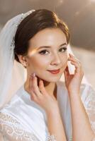 The bride in a silk suit with a veil poses in her room. Morning of the bride. Preparation. Wedding photography photo