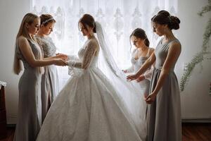 Friends rejoice with the bride in the morning. They take pictures, smile, help the bride fasten her dress. photo